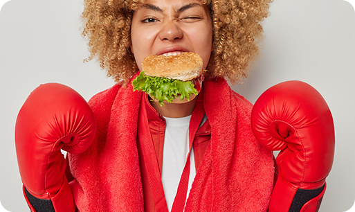 Woman wearing boxing gloves eating a chicken burger