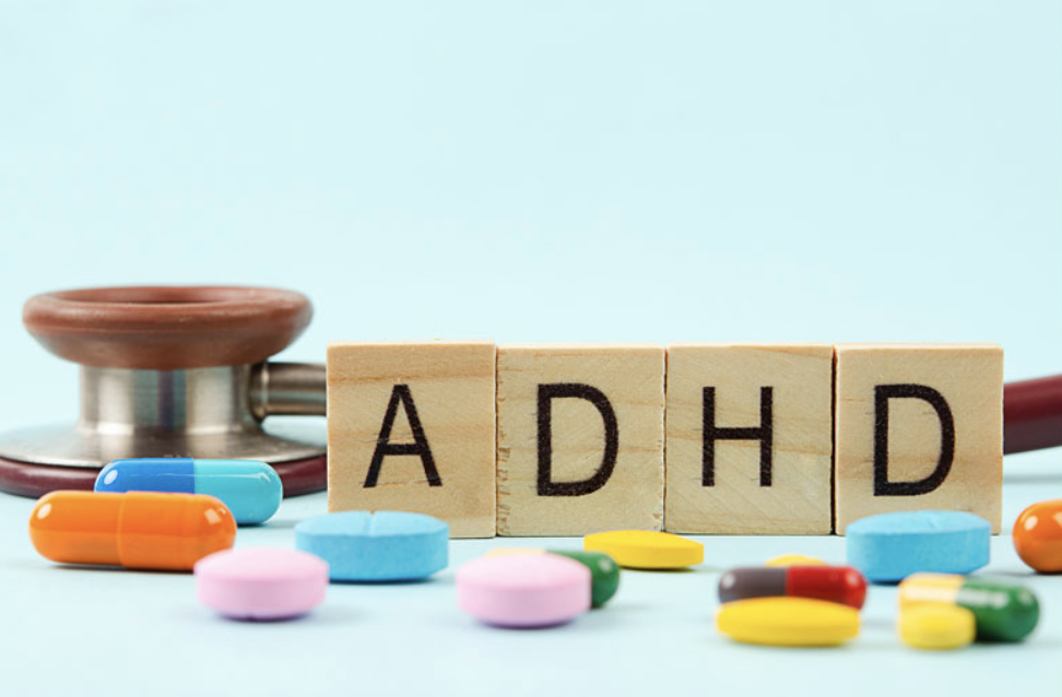 Wooden blocks spelling “ADHD” with doctor’s stethoscope and tablets