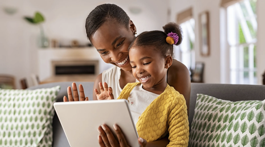 Mother and daughter smiling while using a tablet together